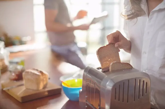 Woman putting bread in toaster,Hamburg, Germany