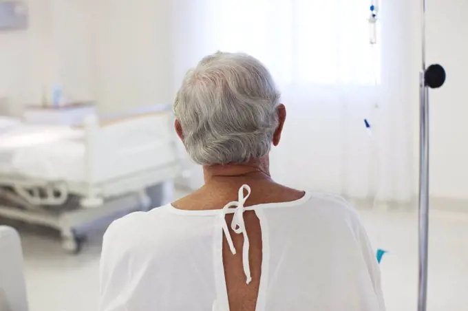 Older patient wearing gown in hospital room