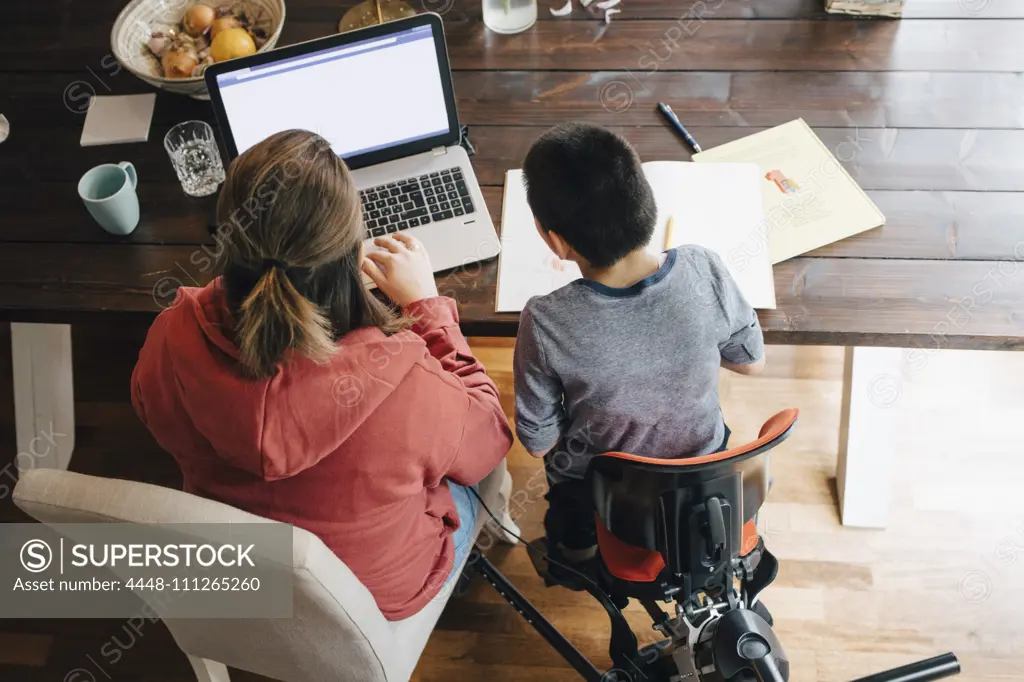 High angle view of mother with autistic son watching video on laptop while sitting at home