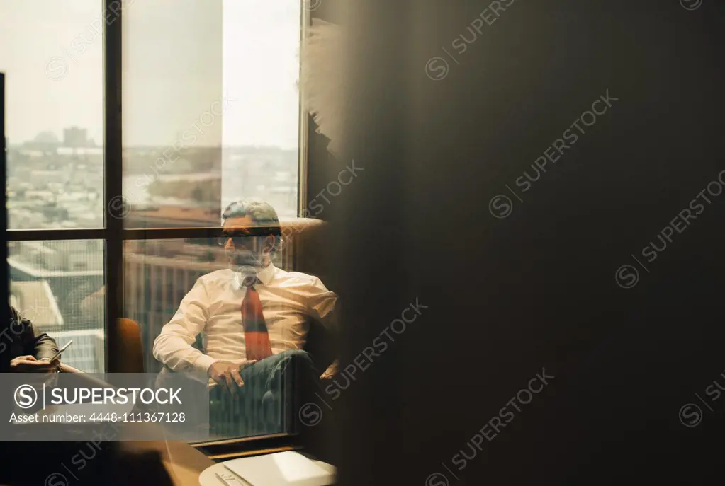 Mature lawyer sitting with colleague in board room at office