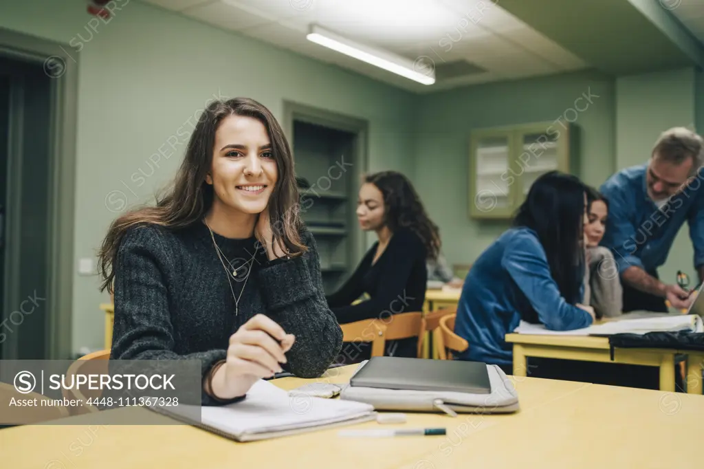 Portrait of smiling female student at desk in classroom