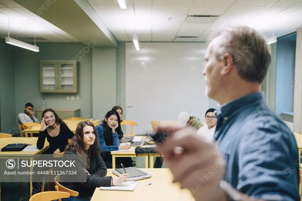 Male teacher teaching high school students in classroom