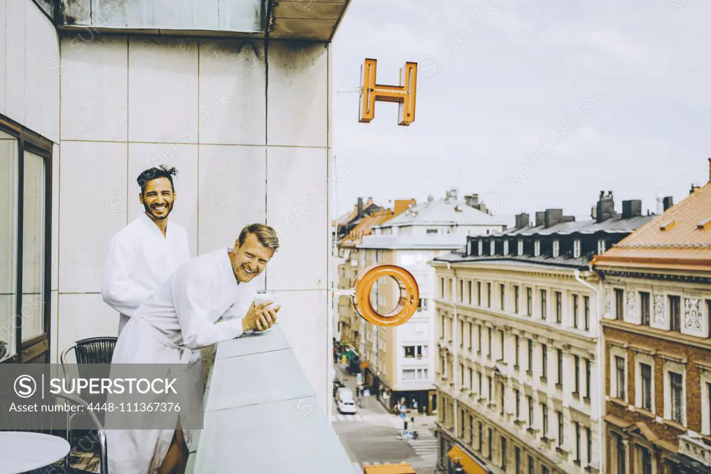 Smiling gay couple enjoying in hotel balcony