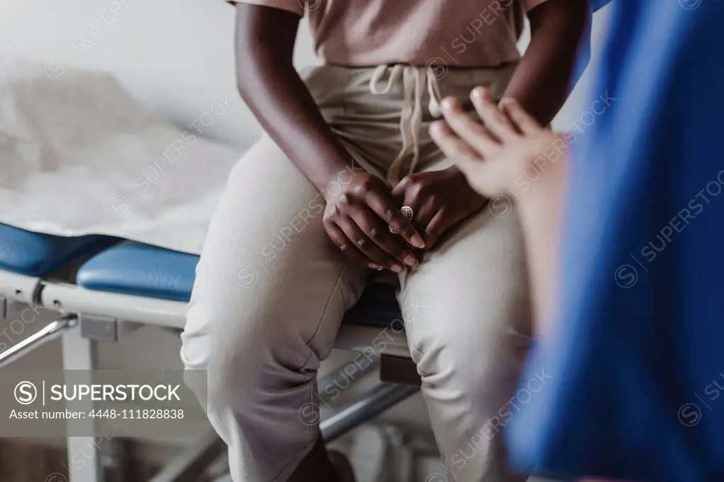 Midsection of female healthcare worker explaining to young patient in medical clinic