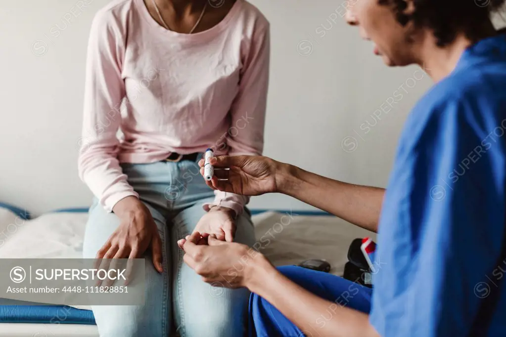 Nurse checking blood sugar of patient in medical examination room