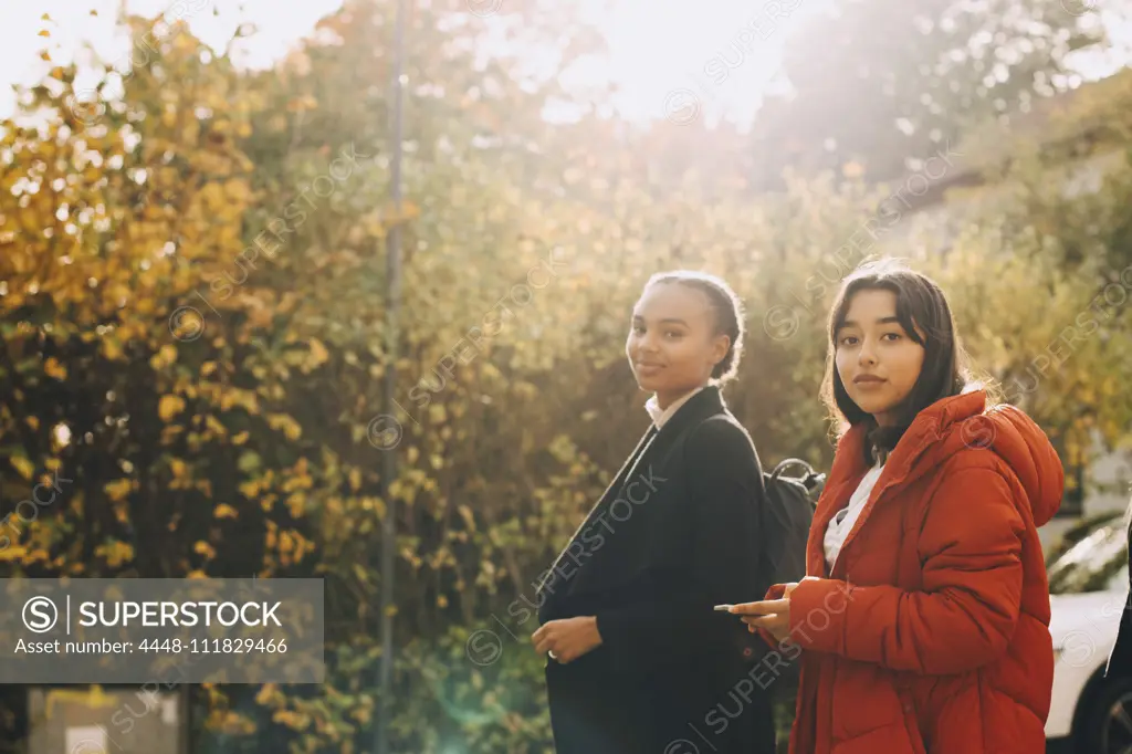 Portrait of teenage girls in jacket against trees during autumn