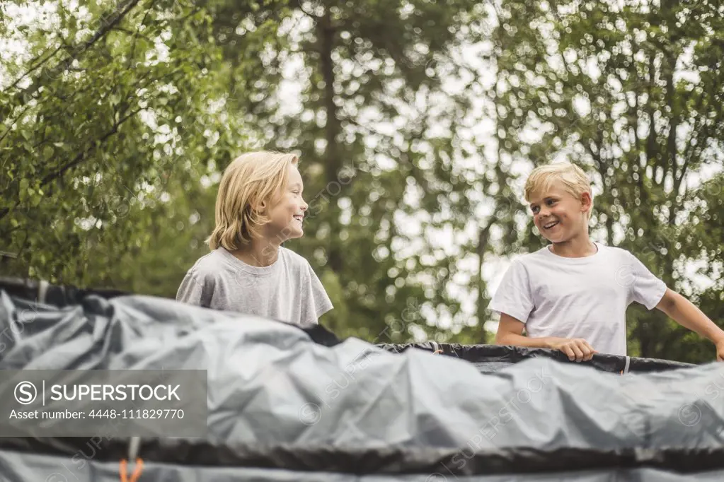 Excited brother and sister pitching tent together at camping site