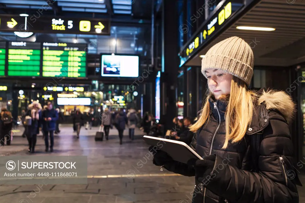 Teenage girl using digital tablet while standing in city during winter