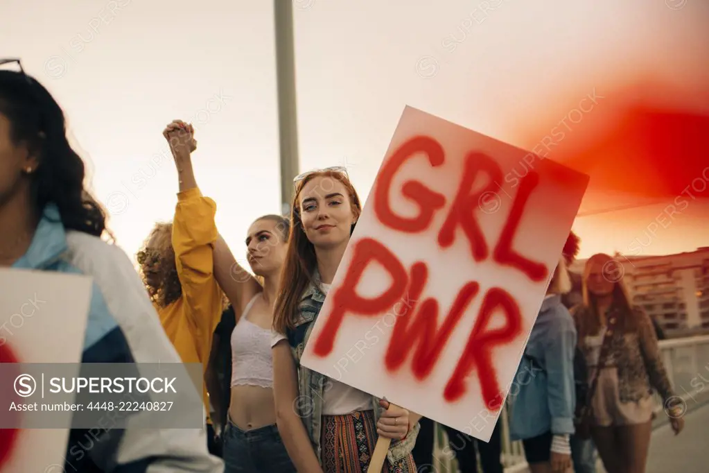 Portrait of women protesting with friends for human rights in city against sky