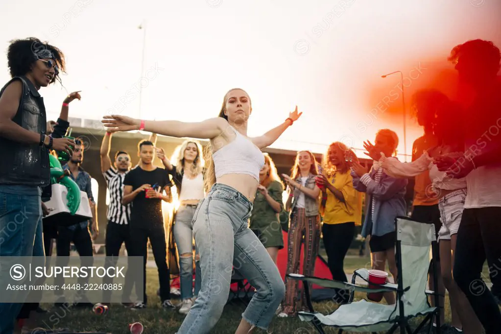 Young woman dancing while friends enjoying in musical event during summer