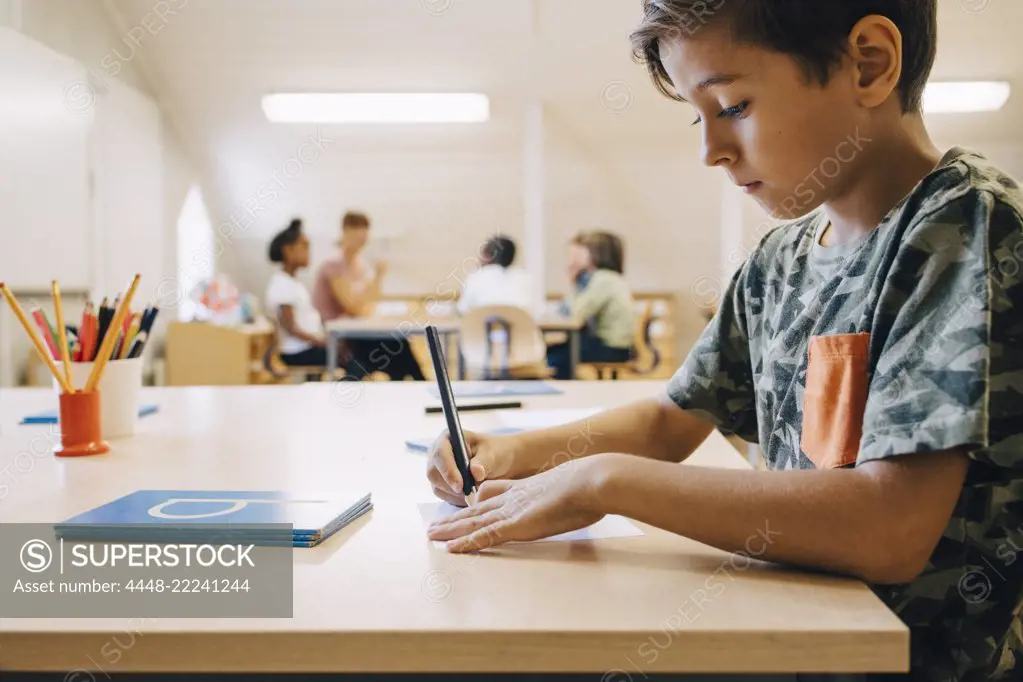 Close-up of boy concentrating while writing on paper at table