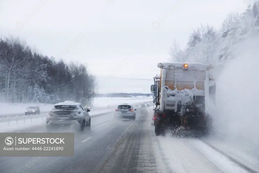 Snowplow and cars moving on snow covered highway