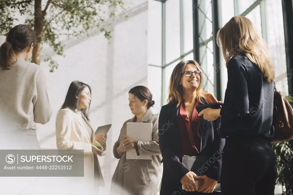 Multi-ethnic female professionals talking at conference event