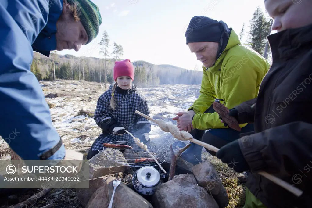 Men cooking while children looking at camping site