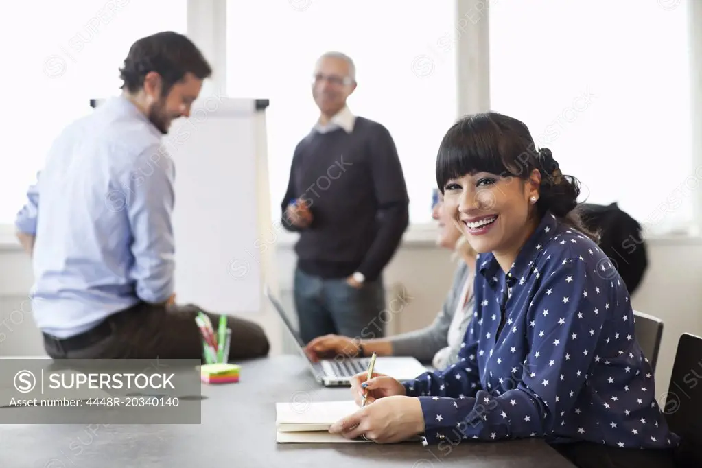 Smiling businesswoman with colleagues in background