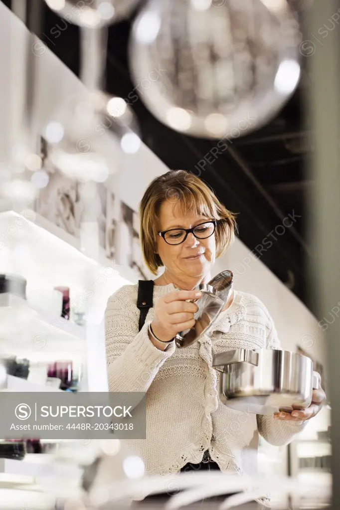 Senior woman buying cookware in shopping mall