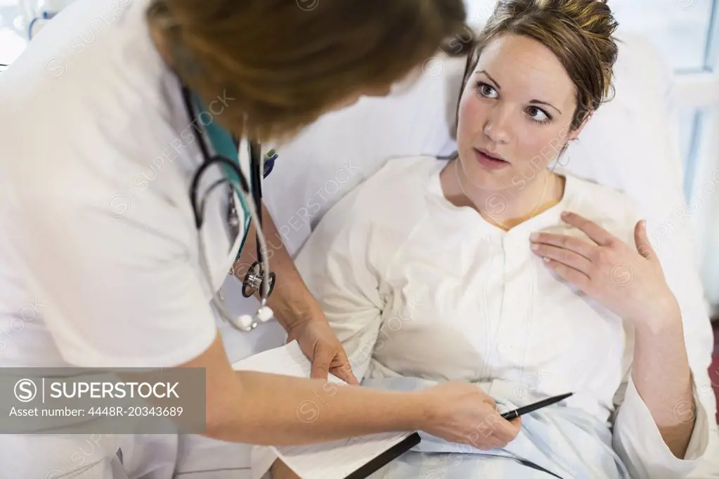 High angle view of female patient communicating with doctor in hospital ward