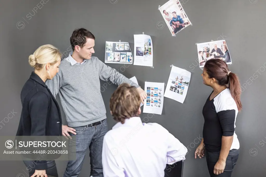 Business colleagues looking at photographs on wall in office