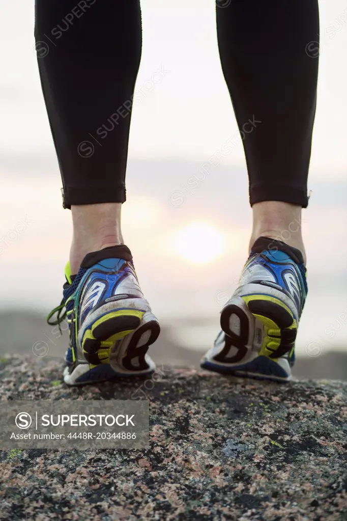 Low section of woman in sports shoes standing on toes outdoors