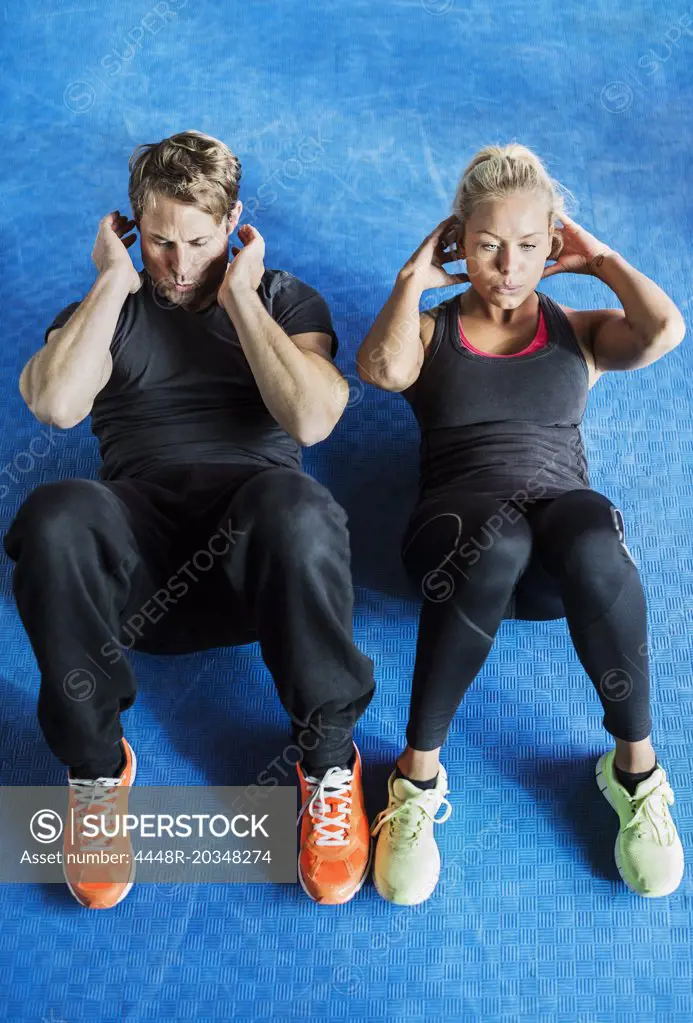 High angle view of friends doing sit-ups at gym