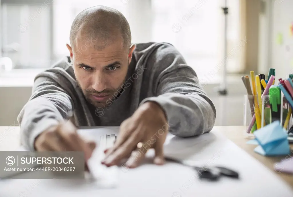 Businessman drawing line on paper at desk in creative office