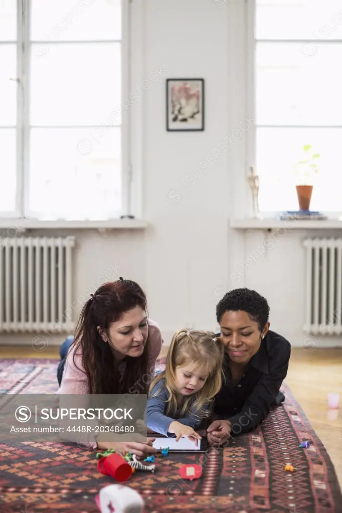 Girl and lesbian couple using digital tablet in living room