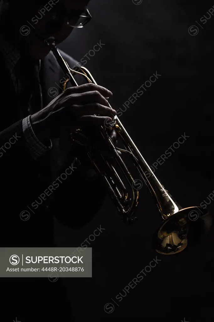 Musician playing trumpet over black background