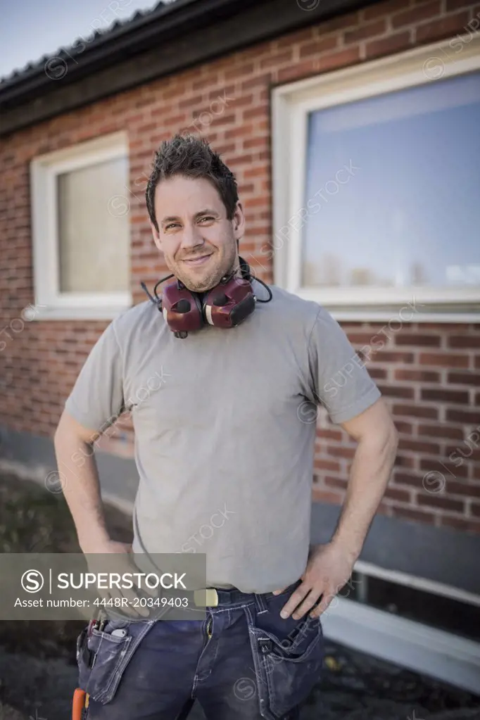 Portrait of confident carpenter standing at construction site