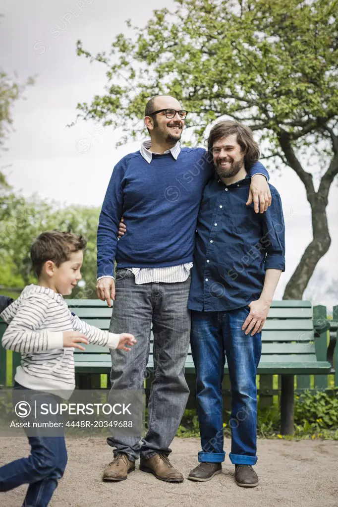 Affectionate gay couple with son playing in park