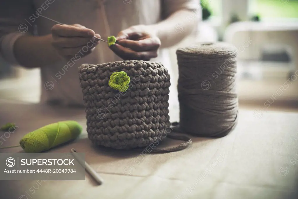 Midsection of woman knitting woolen purse at home