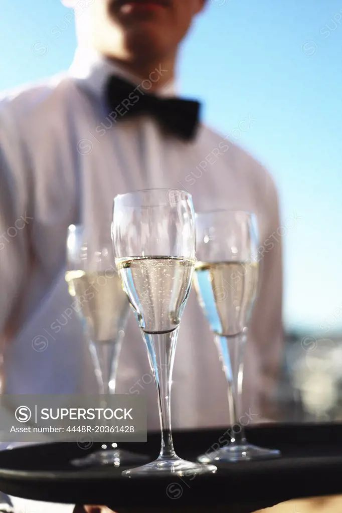 Midsection of waiter serving champagne outdoors