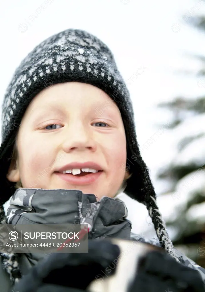 Boy with hat holding thermos mug