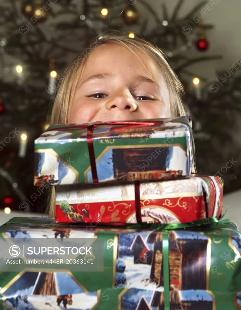 Girl looking out from pile of Christmas gifts