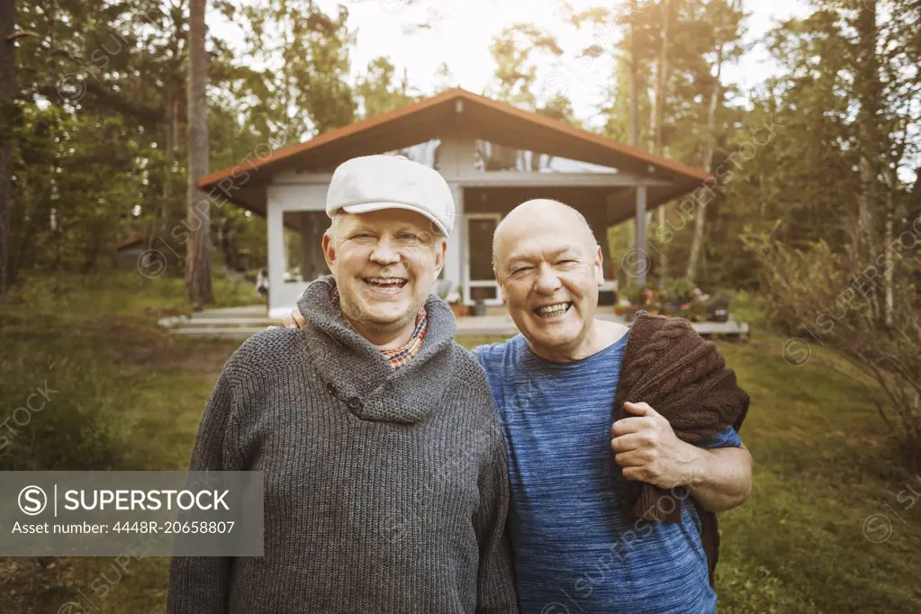 Portrait of happy gay couple standing together at yard