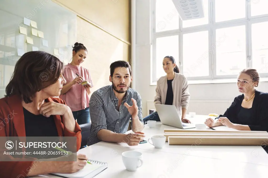 Businessman explaining new project to female colleagues at conference table