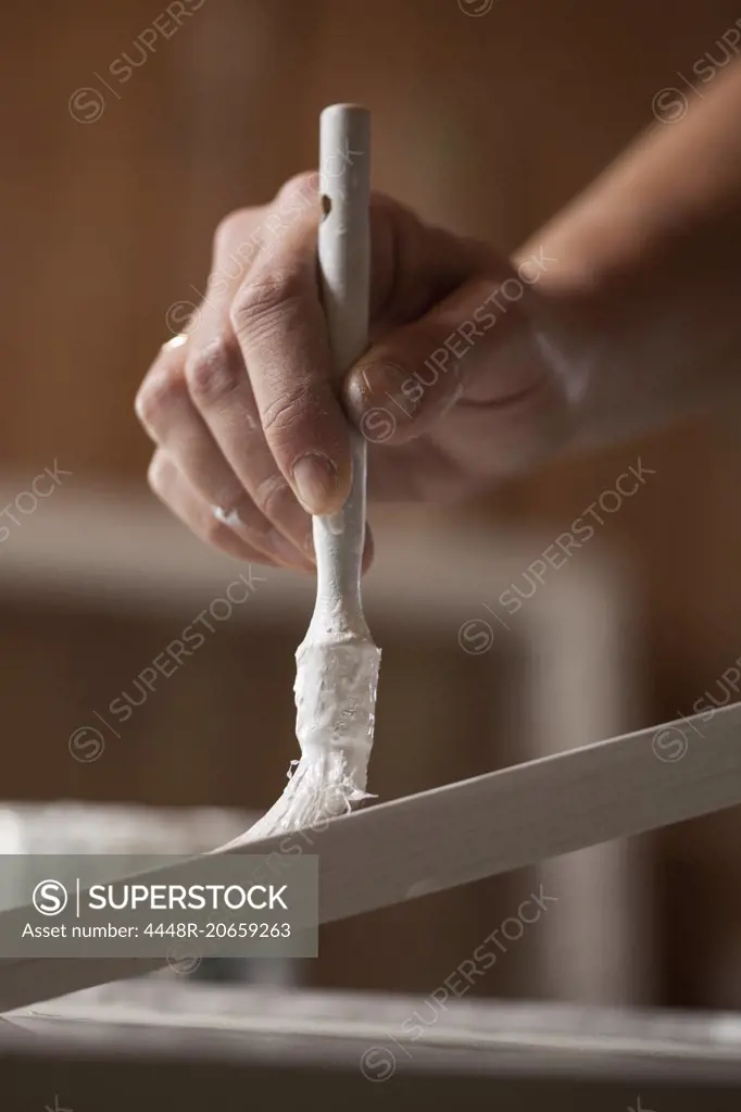 Cropped image of female upholsterer painting wooden plank