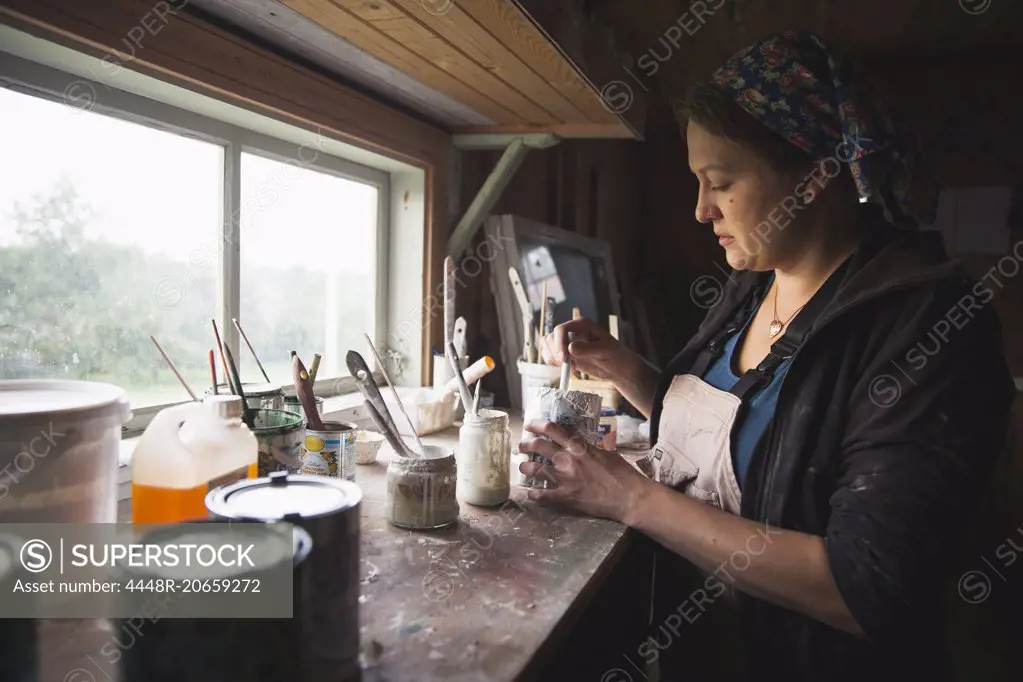 Side view of female upholsterer mixing paint at table