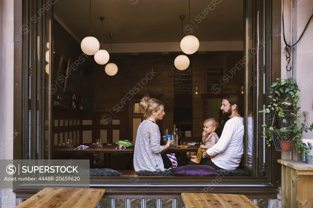 Mid adult parents with son in restaurant seen through window