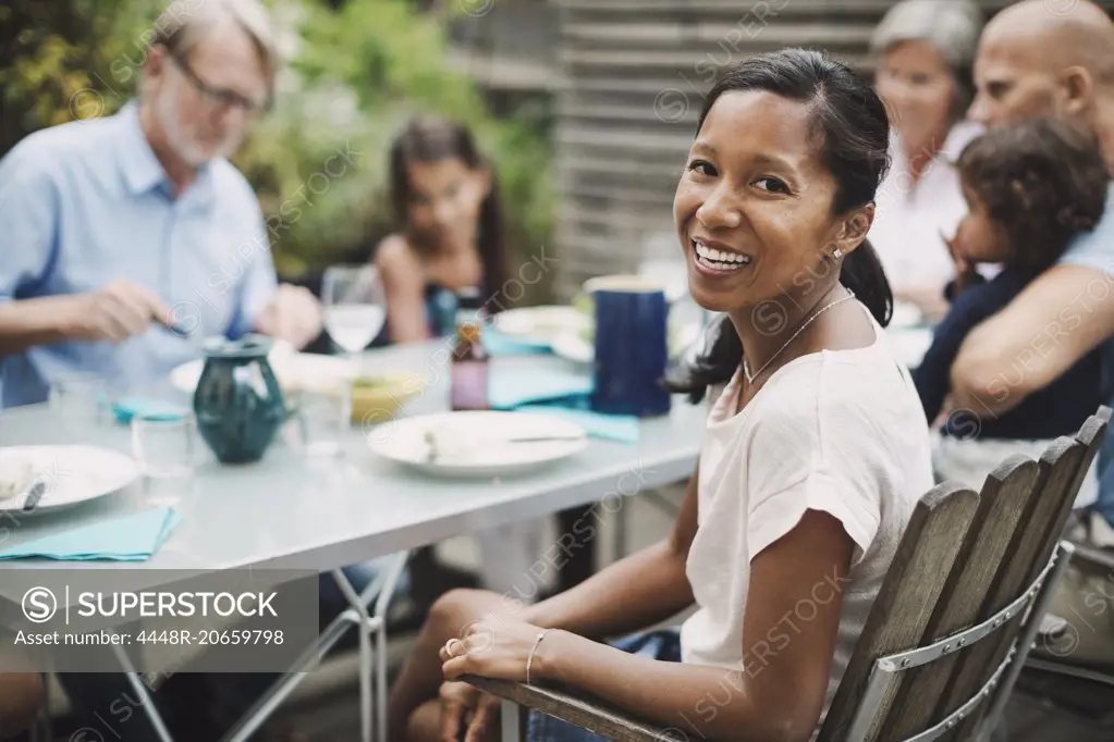 Portrait of happy woman sitting with family at outdoor dining table