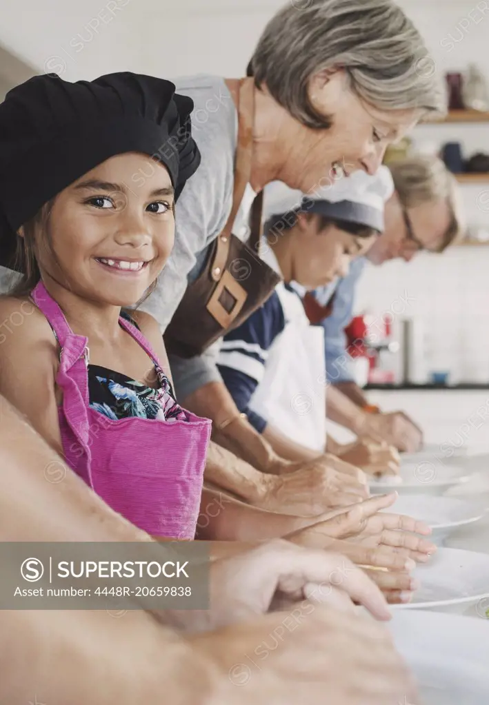 Portrait of happy girl preparing food with family in kitchen