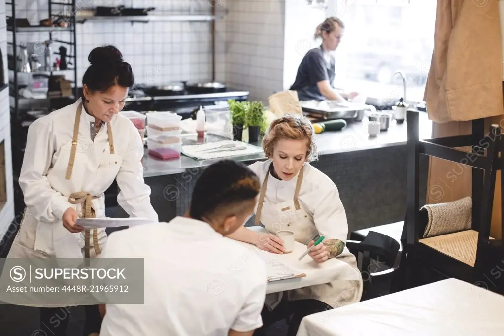 Multi-ethnic restaurant owners discussing while sitting at table