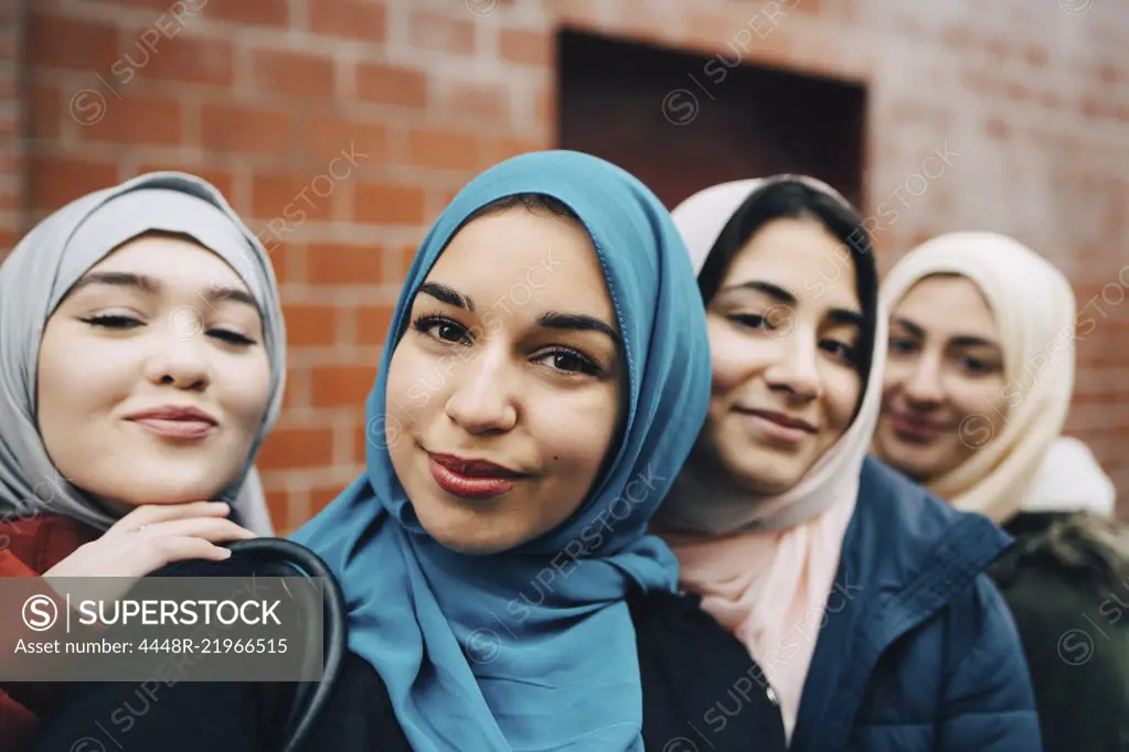 Portrait of smiling Muslim friends against building in city