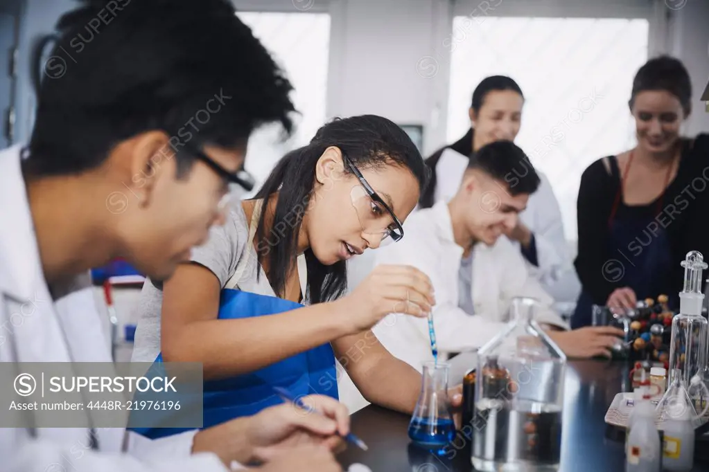 Young multi-ethnic students mixing solutions at chemistry laboratory