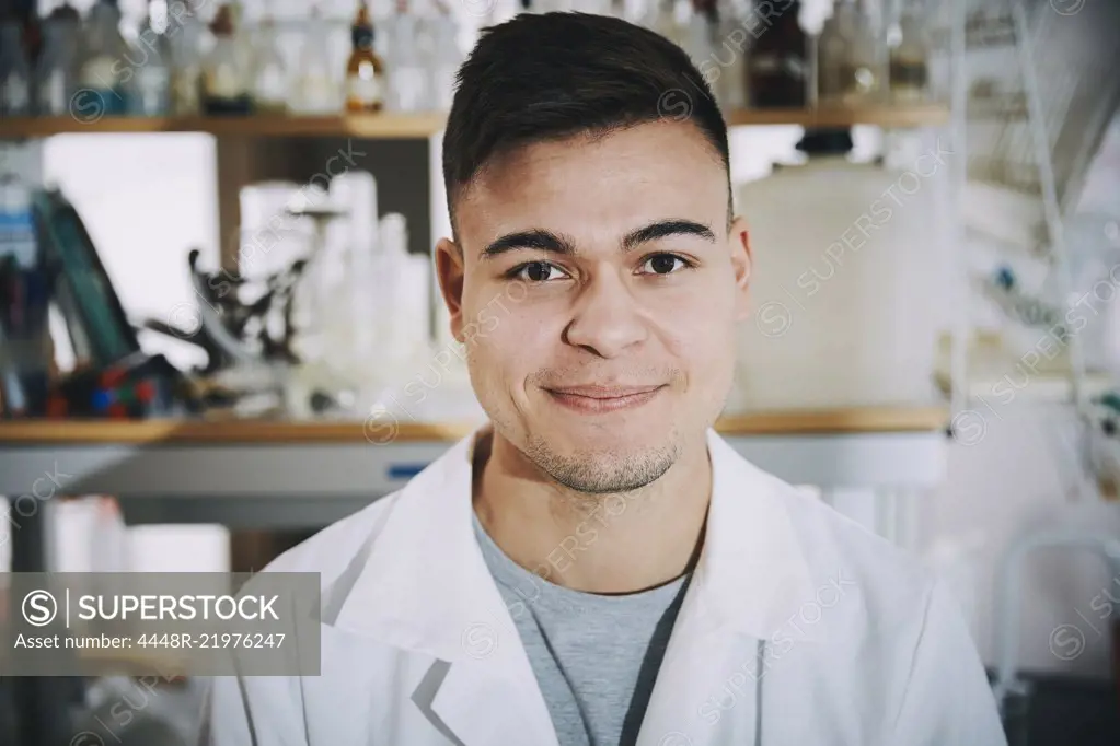 Portrait of confident young male chemistry student standing in college laboratory