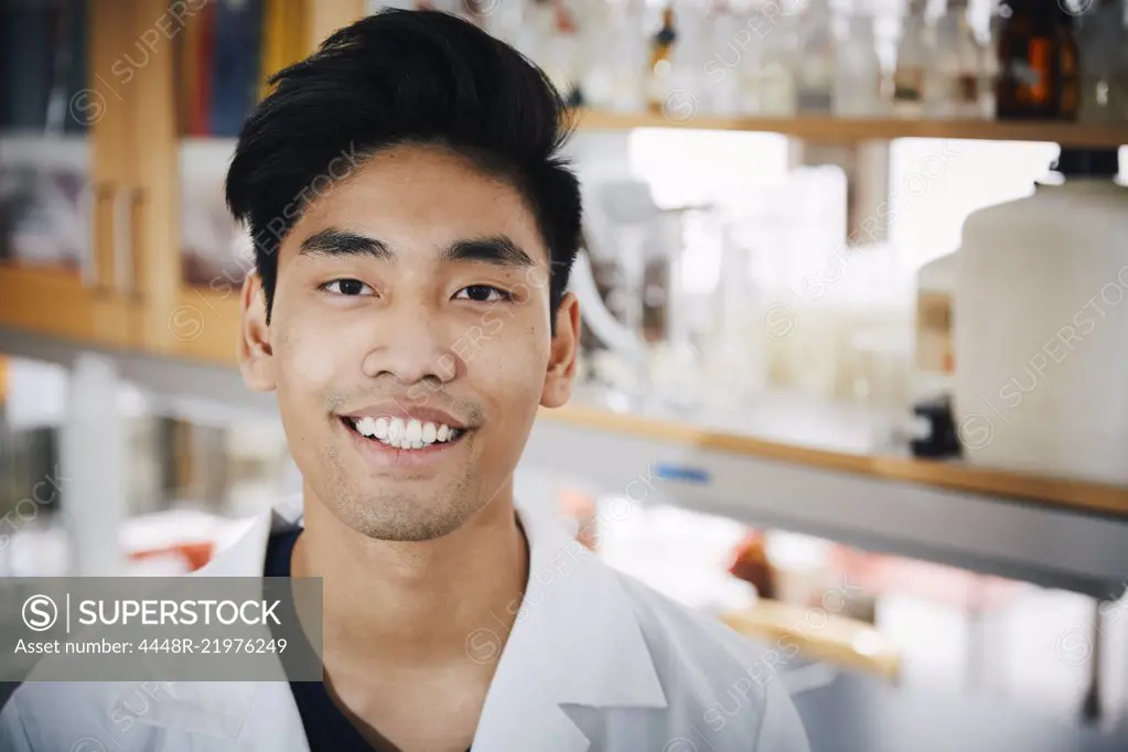 Portrait of confident young male university student standing at chemistry laboratory