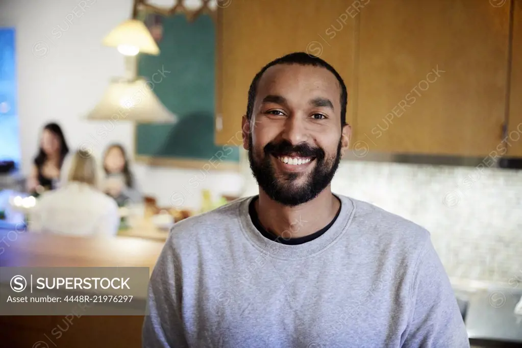 Portrait of smiling mid adult man standing in kitchen at home