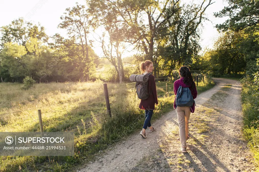 Full length rear view of mother and daughter hiking on dirt road in forest