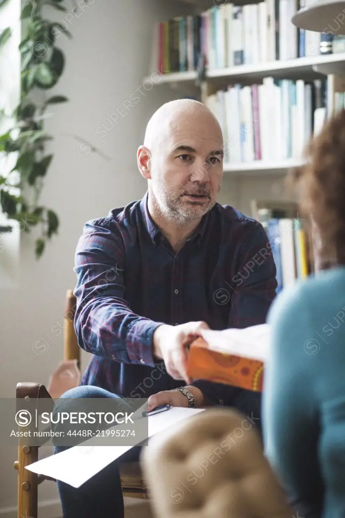 Male therapist giving tissue to female patient during therapy session