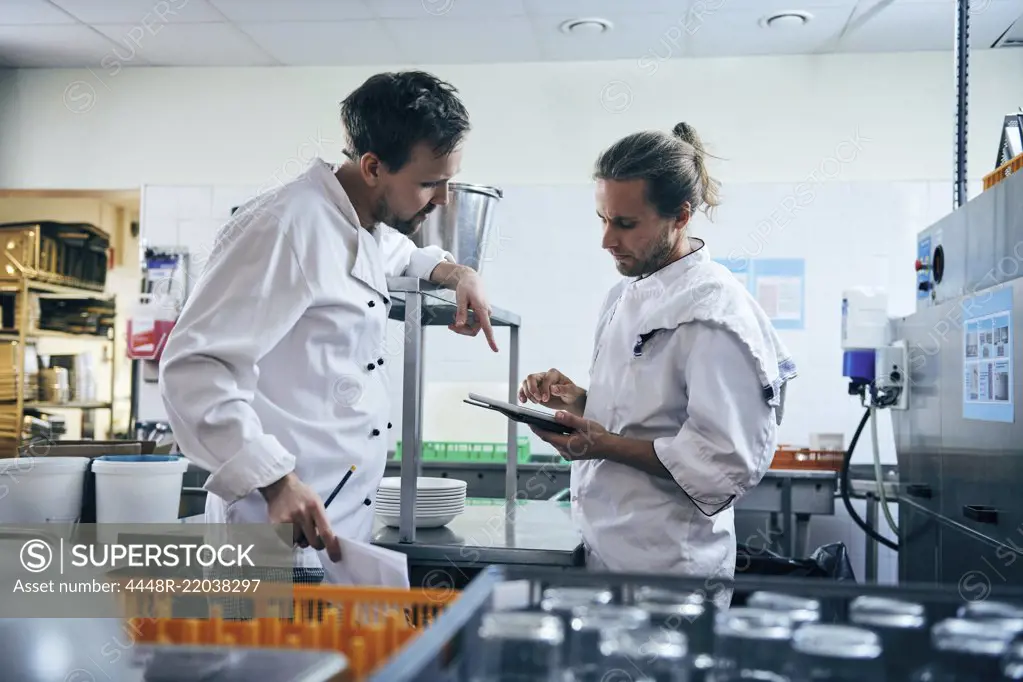 Chefs discussing over digital tablet in kitchen