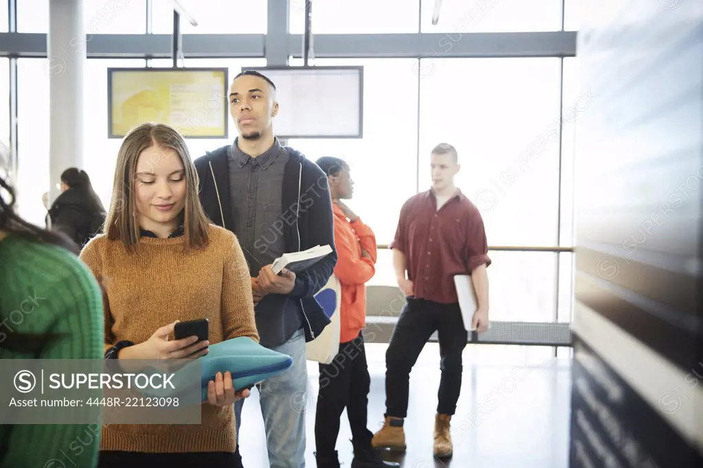 Young male and female students standing in row at university lobby